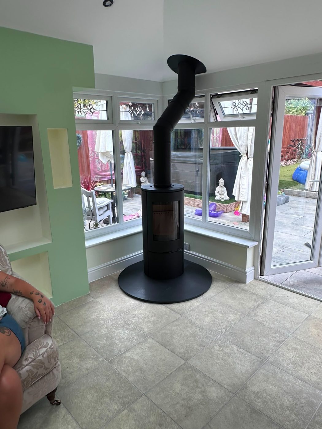 Rotating-style stove on a circular hearth in a bay window room