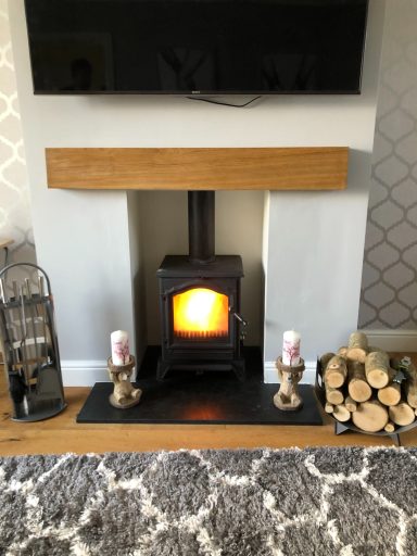 A lit wood burner installed by Flamez in a brick fireplace